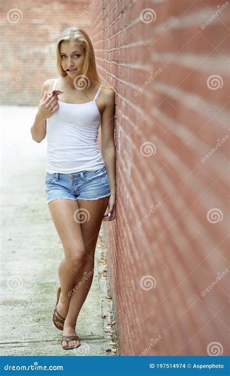Beautiful Blonde Woman In White Tanktop And Denim Shorts Stock Photo