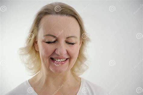 face of a middle aged woman with blond hair on a white background close up she lowered her eyes