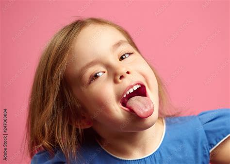 Close Up Shot Of Little Girl With Her Tongue Out Over Pink Isolated