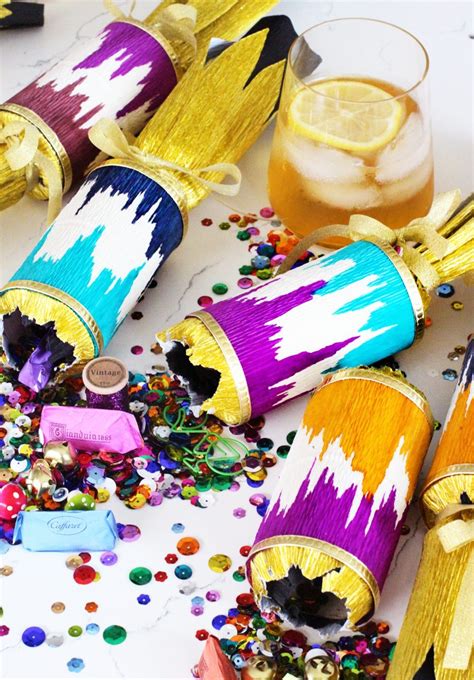 Group of older friends pulling christmas crackers at a dinner party. DIY Ikat Christmas Cracker Party Favor - HonestlyYUM