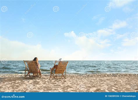 Young Relaxing In Deck Chairs On Beach Near Sea Stock Photo Image