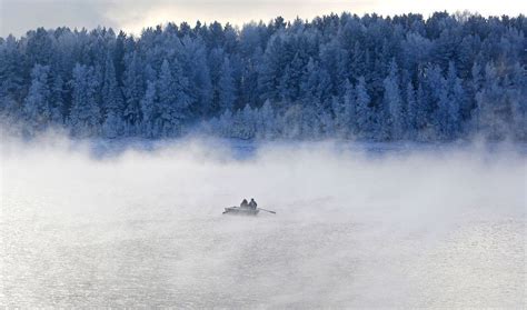 Two Men Row A Boat Through A Frosty Fog Along The Yenisei River At Air