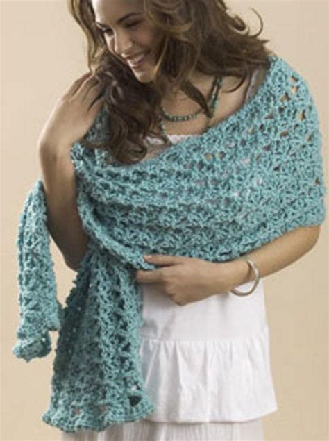 A Woman Wearing A Blue Crocheted Shawl And White Dress With Her Hands