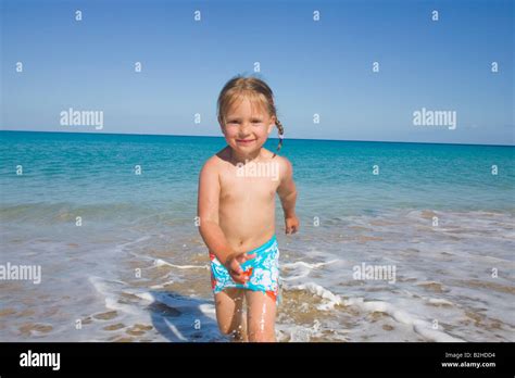 Portrait Of Little Girl Walking Through Surf On Beach Stock Photo Alamy