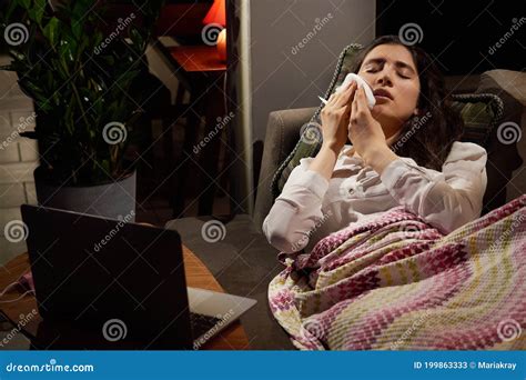 Young Woman On Sofa Covered With A Blanket Freezing Blowing Running