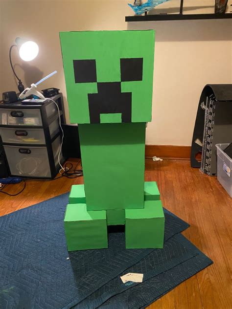 A Green Creeper Made Out Of Paper Sitting On Top Of A Blue Mat In A Room