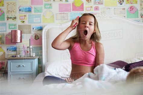 Young Girl Sitting On Bed And Brushing Hair Whilst Yawning Stock