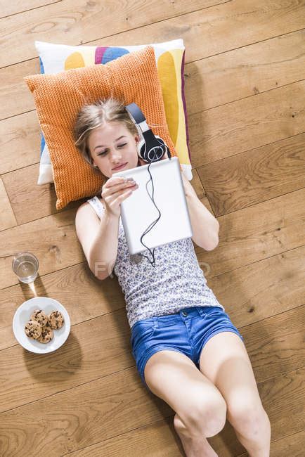 Teenage Girl Lying On Floor Listening To Music From Digital Tablet Listening Music