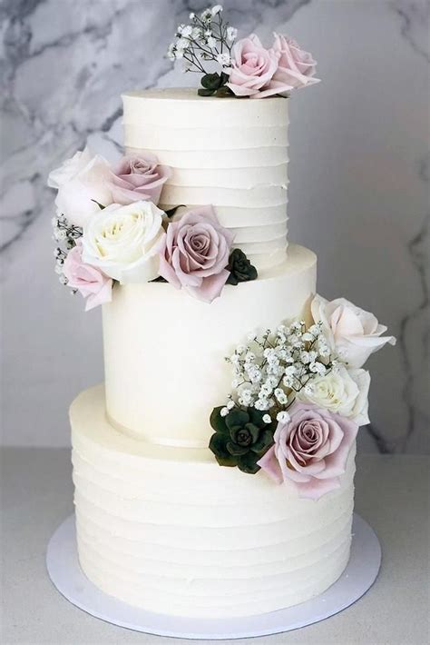A Three Tiered White Cake With Flowers On Top