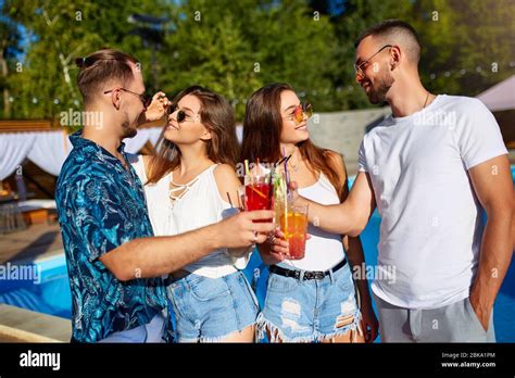 Group Of Friends Having Fun At Poolside Summer Party Clinking Glasses