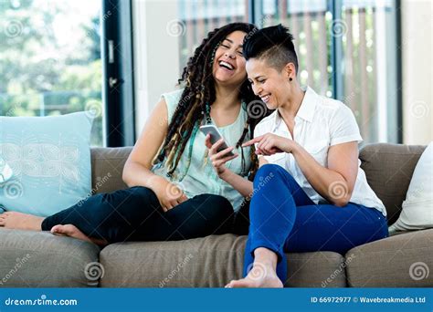 Lesbian Couple Looking At Mobile Phone And Smiling Stock Image Image