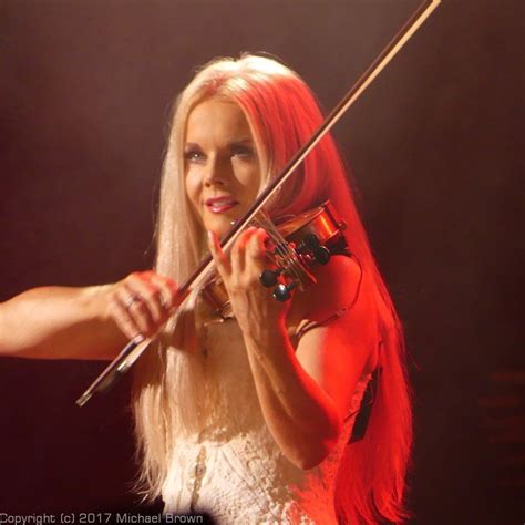 A Woman With Long Blonde Hair Holding A Violin