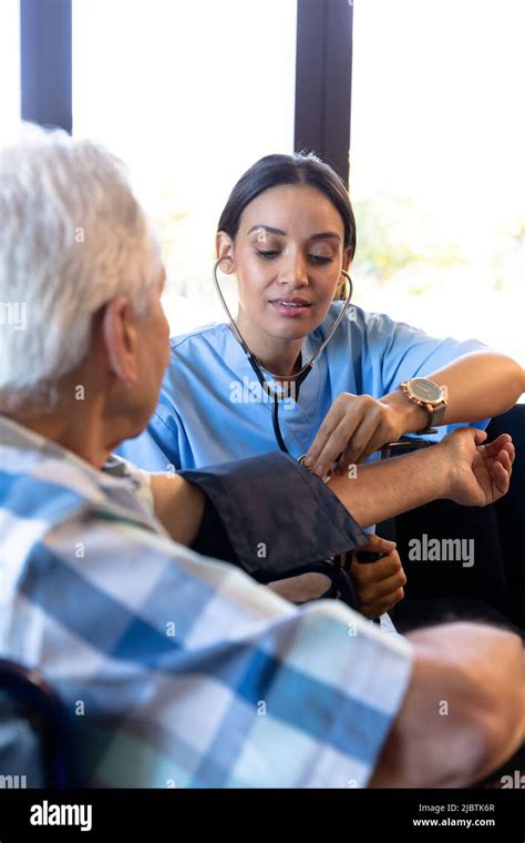 Biracial Female Doctor Examining Caucasian Senior Mans Blood Pressure