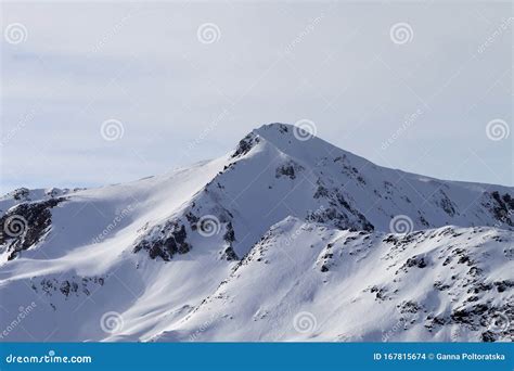 Snowy Slope At High Winter Mountains And Sunlit Cloudy Sky Stock Photo