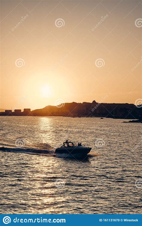 Vertical Shot Of A Boat Sailing On The Sea With The Sun