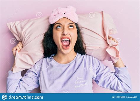 beautiful middle eastern woman wearing sleep mask and pajama sleeping on pillow angry and mad