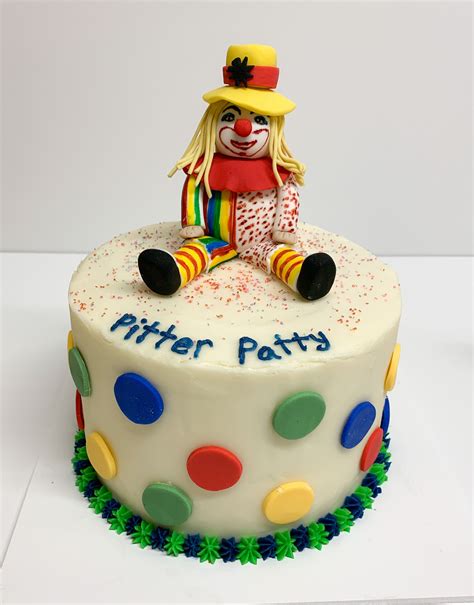 A Birthday Cake Decorated With A Clown Sitting On Its Side And The Words Pitter Patta