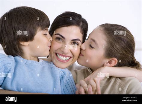 Mother Being Kissed On Each Cheek By Young Daughter And Son Smiling