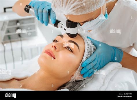 Skilled Female Dermatologist Using Modern Professional Equipment Stock