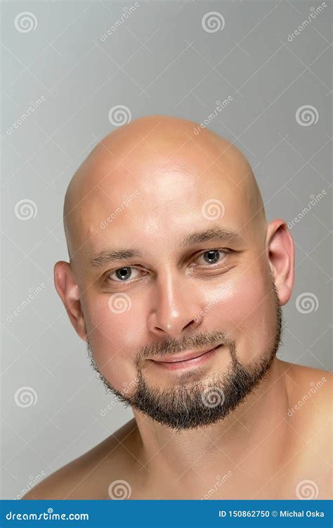 Attractive Smiling Bald Man On Gray Background In Studio Stock Photo