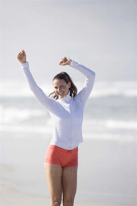 Young Woman On Beach Arms Up Stock Photo