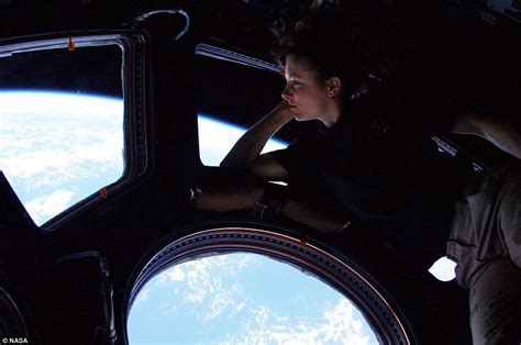 Female Astronaut Looks Down At Earth From Window Of Her Space Station