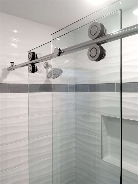 A Glass Shower Door In A Bathroom With White Walls And Grey Trimming On