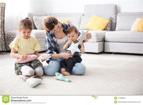 Mother With Cute Little Children Sitting On Cozy Carpet Stock Image