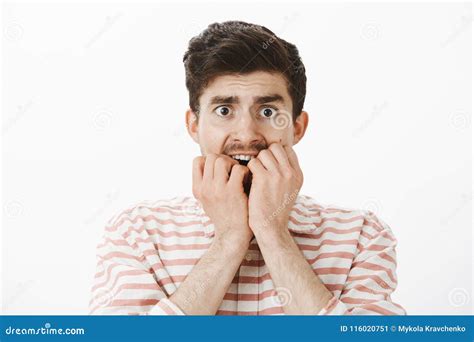 Studio Shot Of Scared Trembling Poor European Guy In Stripes Shirt