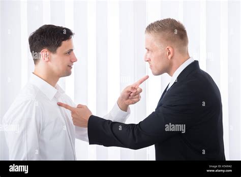 Portrait Of Two Young Businessmen Pointing Finger At Each Other Stock
