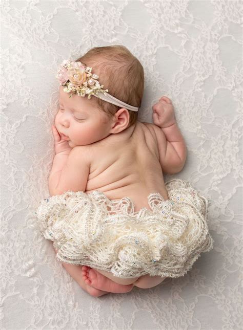 Newborn Baby Girl Sleeping On Her Tummy With A Tutu And Floral Headband