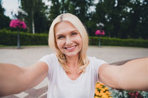 Photo Of Mature Funky Blond Lady Do Selfie Wear White T Shirt Pants Walk In Park Stock Image