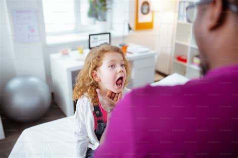 showing throat blue eyed curly girl opening mouth showing her throat while visiting doctor