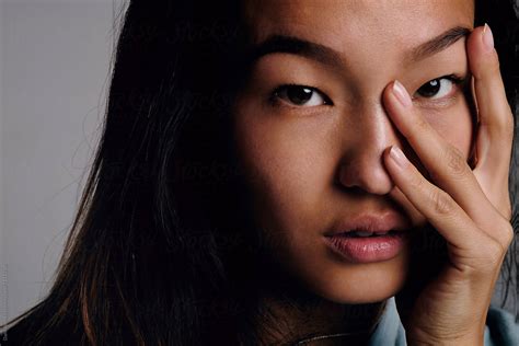 asian girl with fingers on face looking at camera by stocksy contributor danil nevsky stocksy