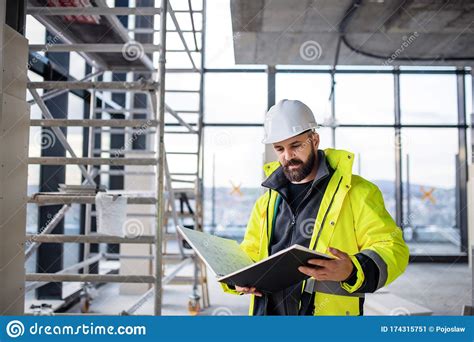 Man Engineer Standing On Construction Site Holding Blueprints Stock