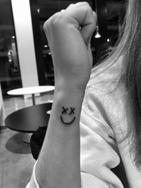 A Woman With A Smiley Face Tattoo On Her Wrist