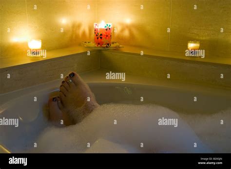 A Womans Feet Poking Through The Bubbles In Her Bath Lit By 3 Candles