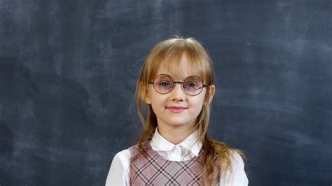 Portrait Shot Of Adorable Little Schoolgirl In Glasses Posing Against