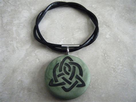 A Stone With A Knot On It Is Sitting On A Black Leather Cord And Sits