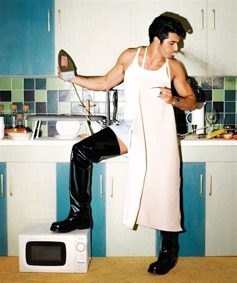 A Man Sitting On Top Of A Microwave In A Kitchen