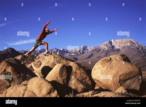 A Man Jumping From Rock To Rock In The Buttermilk Boulders In