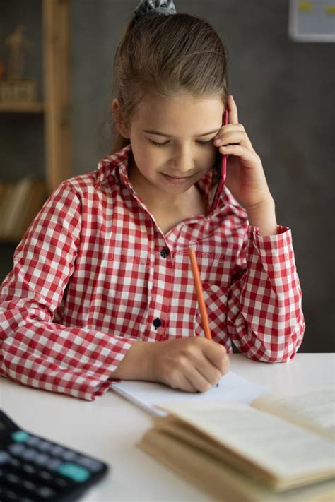 Portrait Of Schoolgirl Talking On The Phone While Studying Remotely