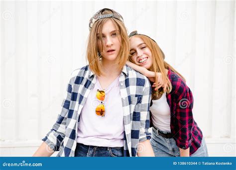 Two Cheerful Funny Girl Wearing Checkered Shirts Posing Against Street
