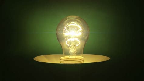Real light bulb turning on, shine and flickering on green ...