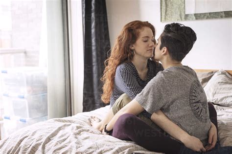 Lesbians Romancing While Relaxing On Bed At Home Stock Photo