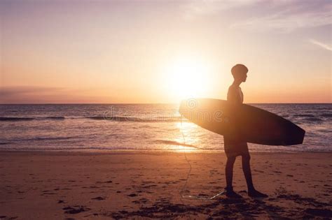 Silhouette Of Surfer Man Carrying Their Surfboards On Sunset Beach With