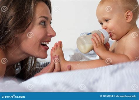 Baby Drinking From Bottle With Mother Smiling Stock Photo Image Of