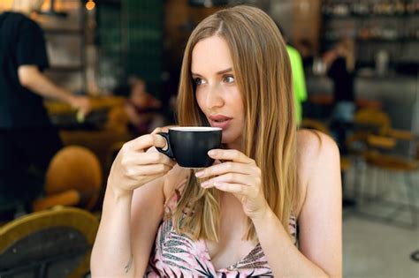 Innenporträt einer hübschen blonden frau im restaurant leckeren cappuccino trinkt ihr