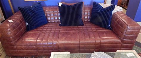 A Brown Leather Couch With Blue Pillows On It