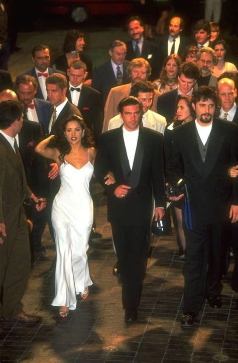 A Group Of People Walking Down A Street Next To Each Other In Tuxedos